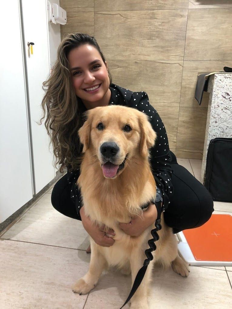 Veterinária da Movimento Animal abraçando um golden retriever